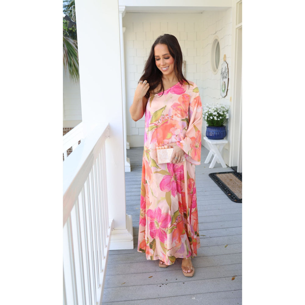 Woman in a floral dress standing on a wooden deck.