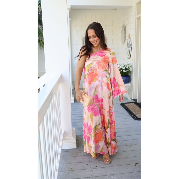 Woman wearing a floral dress standing on a porch.