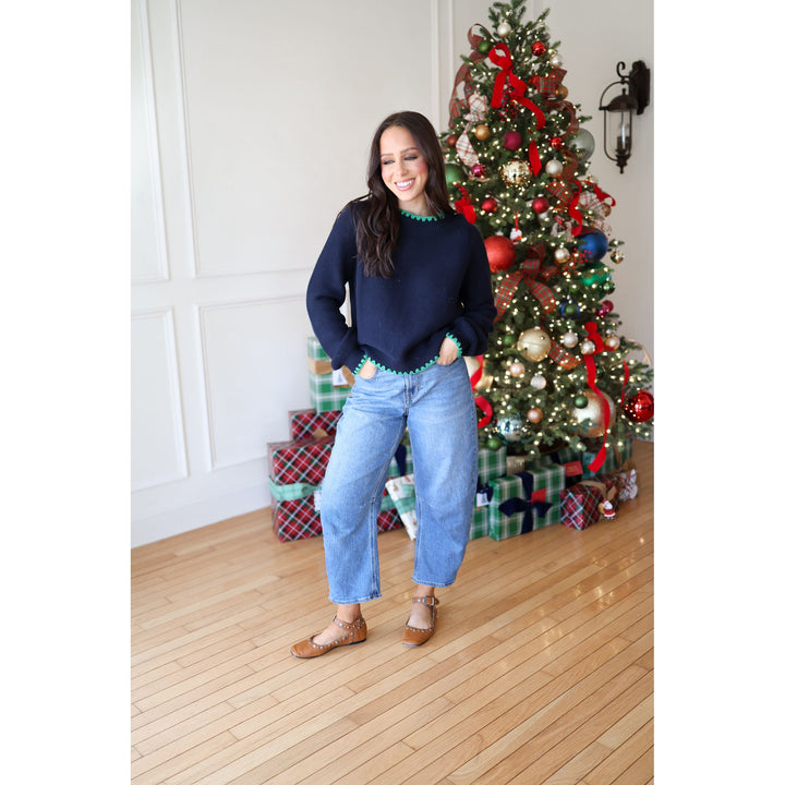 Woman standing in front of a decorated Christmas tree with presents underneath.