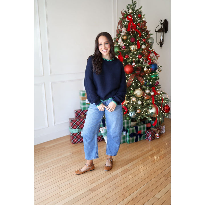 Woman posing in front of a decorated Christmas tree with presents underneath.