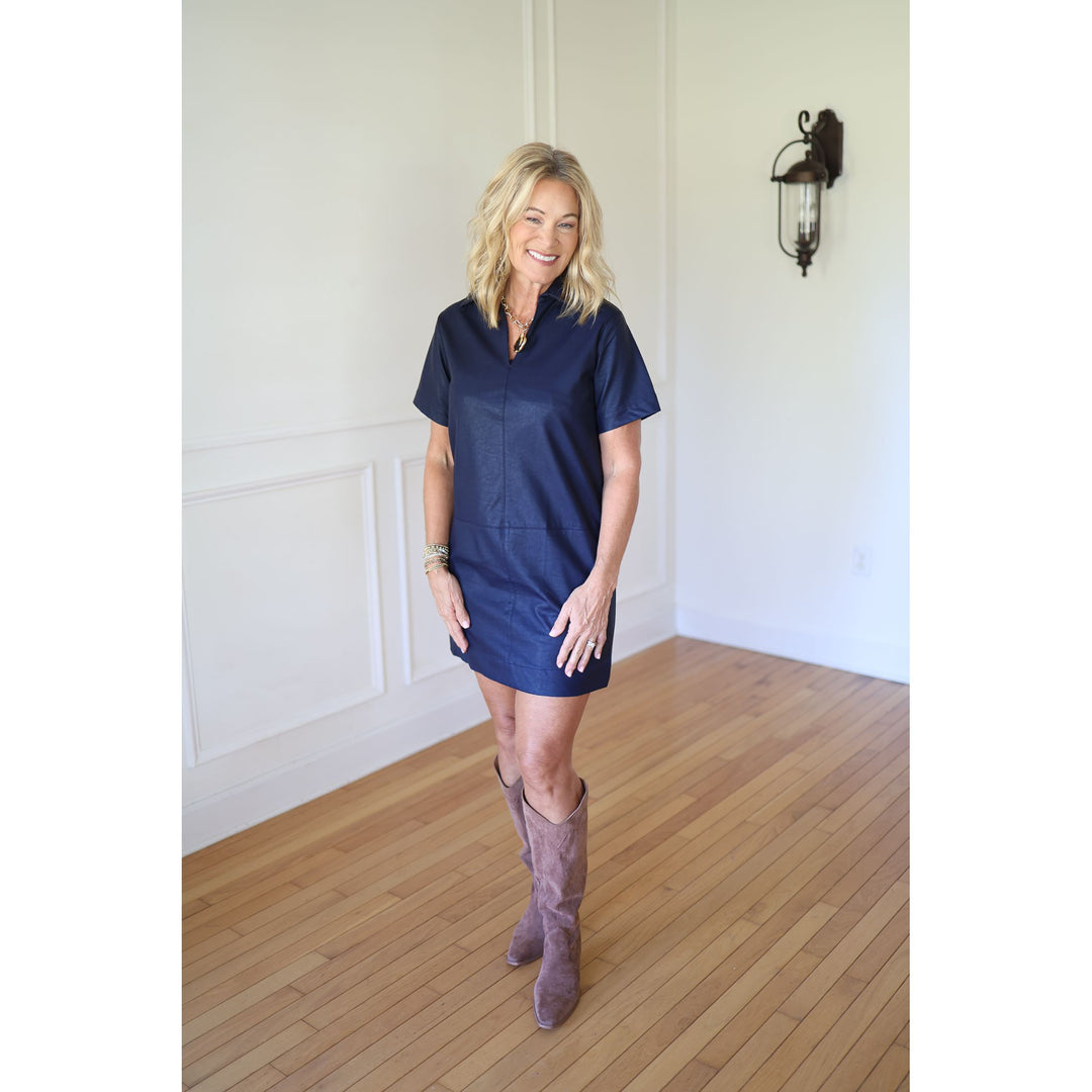 Woman wearing a navy dress and brown knee-high boots 