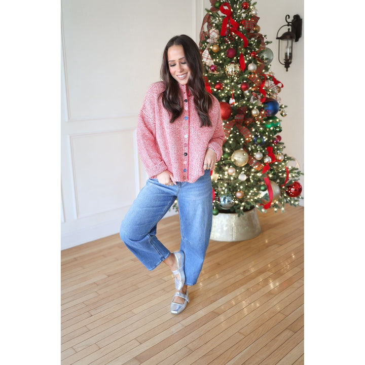 Woman in a red plaid shirt and blue jeans standing in front of a decorated Christmas tree.