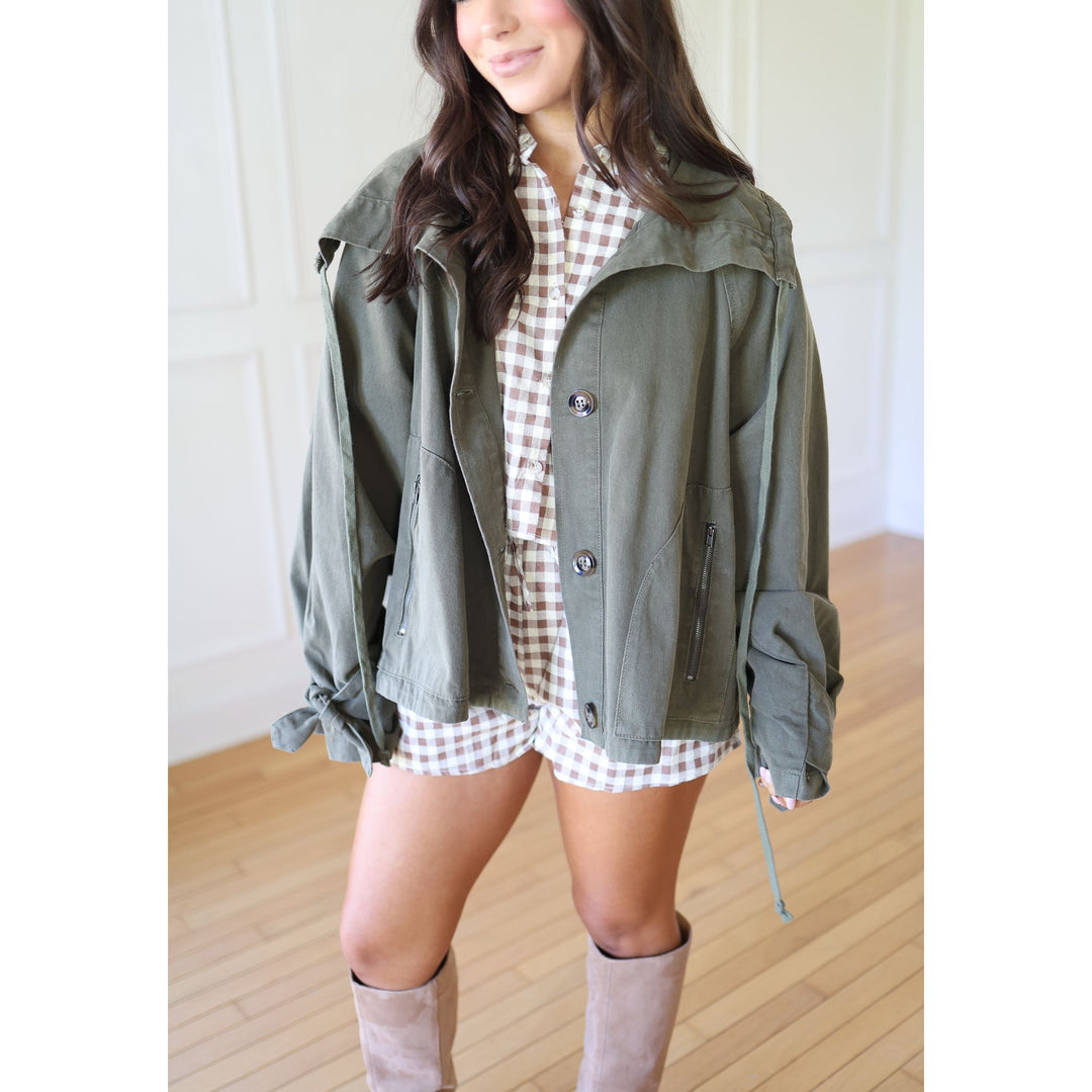 Person wearing a green jacket over a plaid dress with knee-high boots 