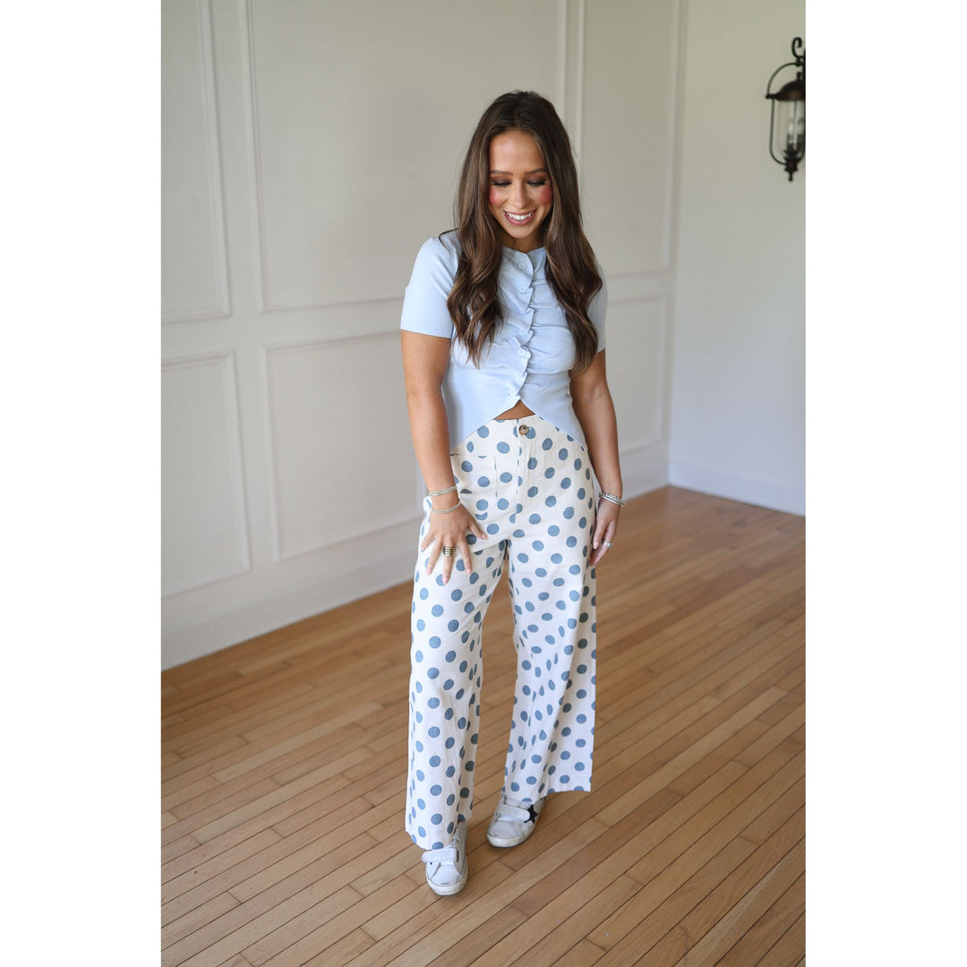 Woman wearing a light blue top and white pants with blue polka dots 