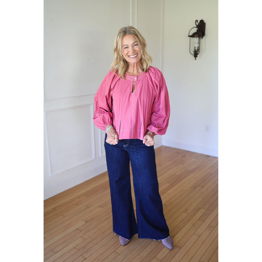 Woman wearing a pink blouse and blue jeans 