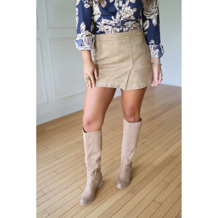 Person wearing a beige skirt and knee-high boots .