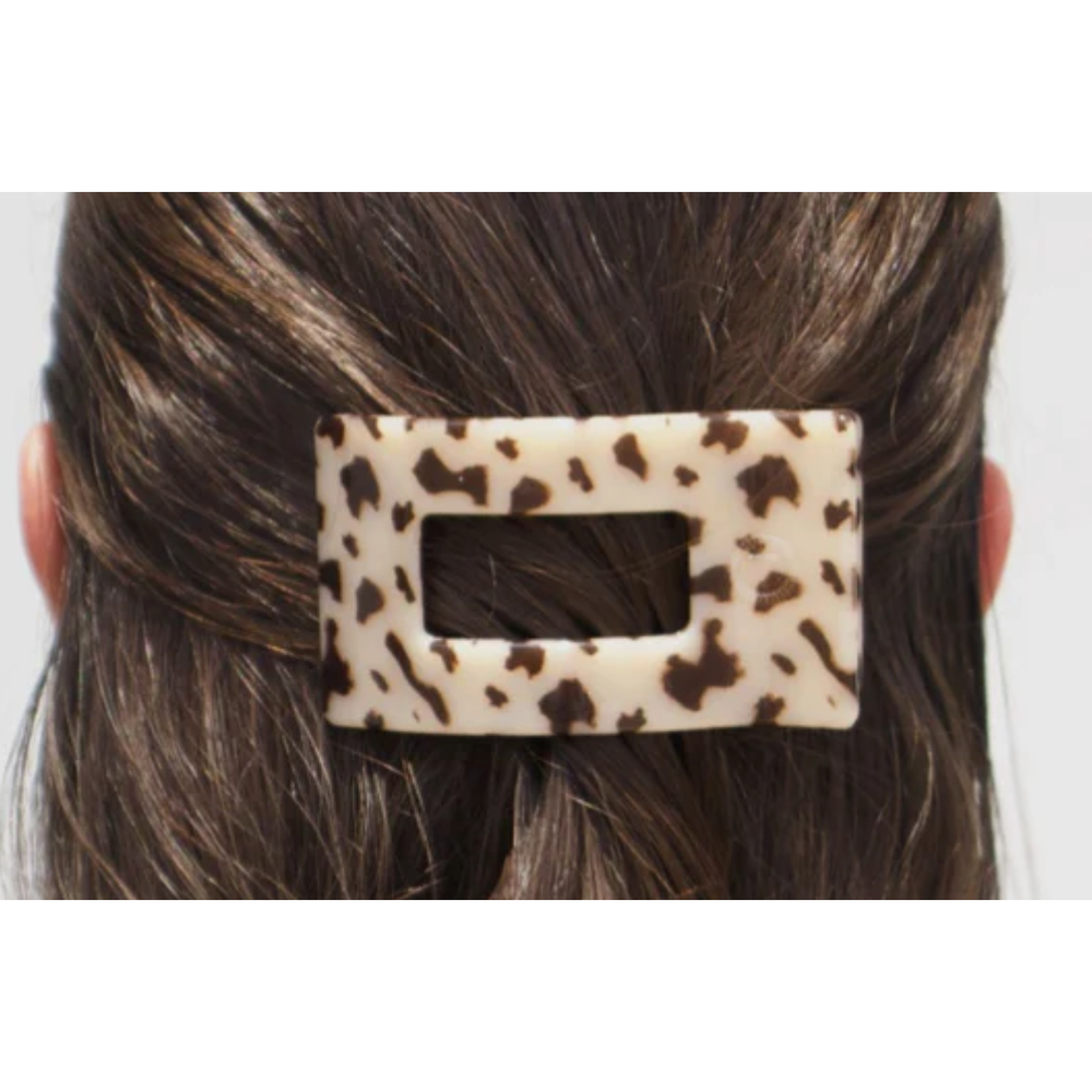 Leopard print hair clip on a person's hair against a white background