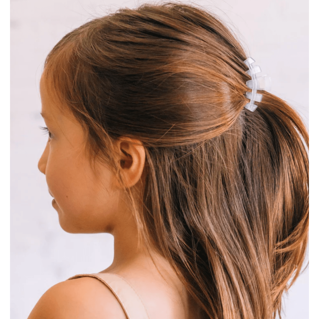 Close-up of a person with brown hair tied in a ponytail using a white hair clip on a light background