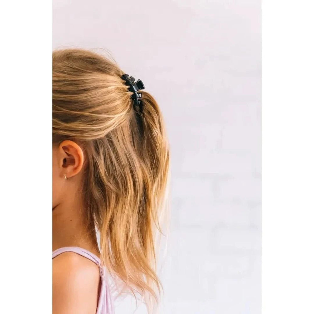 Person with blonde hair tied in a ponytail against a white background
