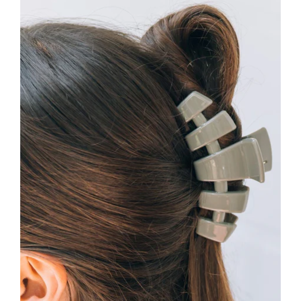 Metallic hair clip in a person's hair against a white background