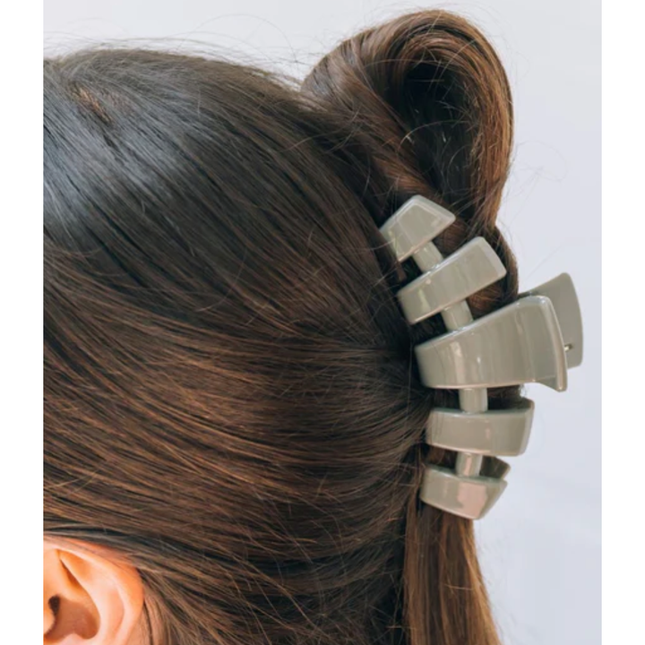 Metallic hair clip in a person's hair against a white background