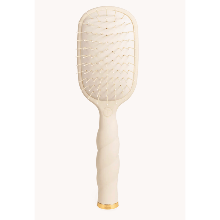Beige paddle hairbrush with gold accents on a white background