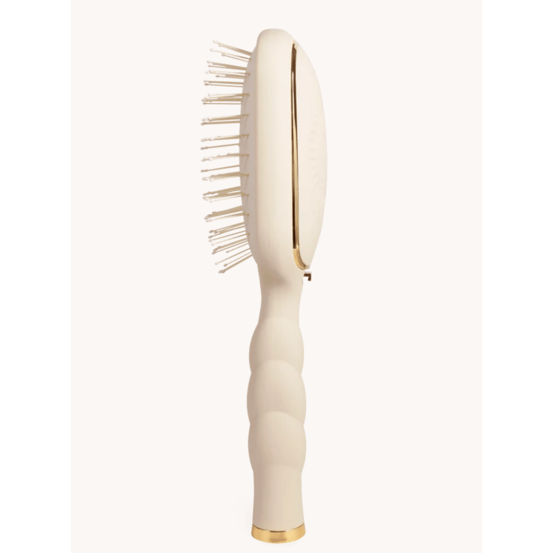 Beige hairbrush with gold accents on a white background