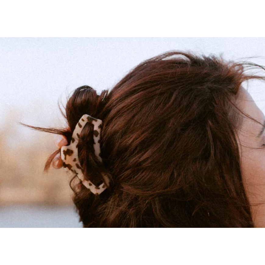 Close-up of a person's hair with a decorative clip against a blurred background