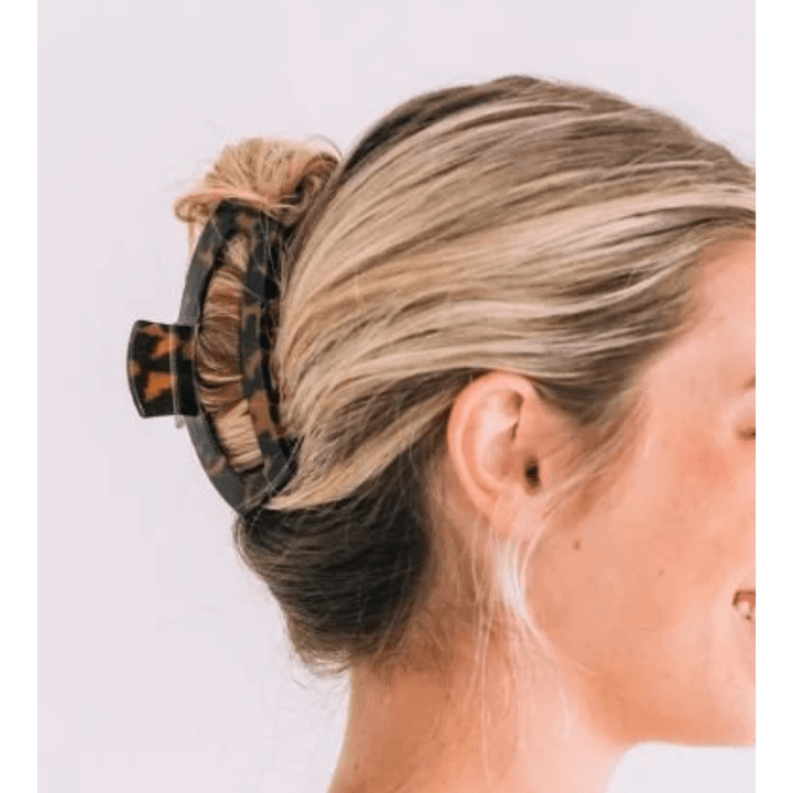 Person with blonde hair tied up with a tortoiseshell scrunchie against a white background
