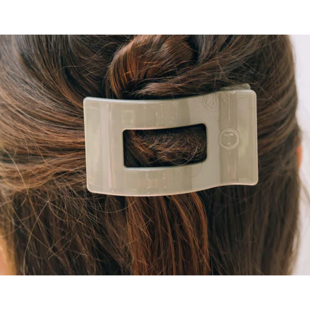 Metallic hair clip on a person's hair against a white background