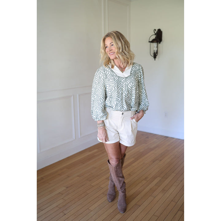 Woman wearing a patterned top, white shorts, and brown knee-high boots