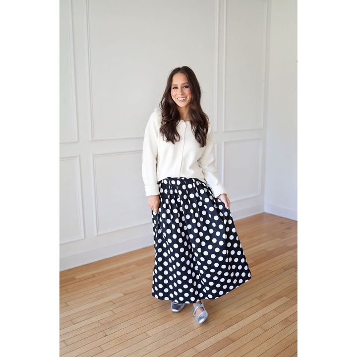 Woman wearing a white blouse and black polka dot skirt 