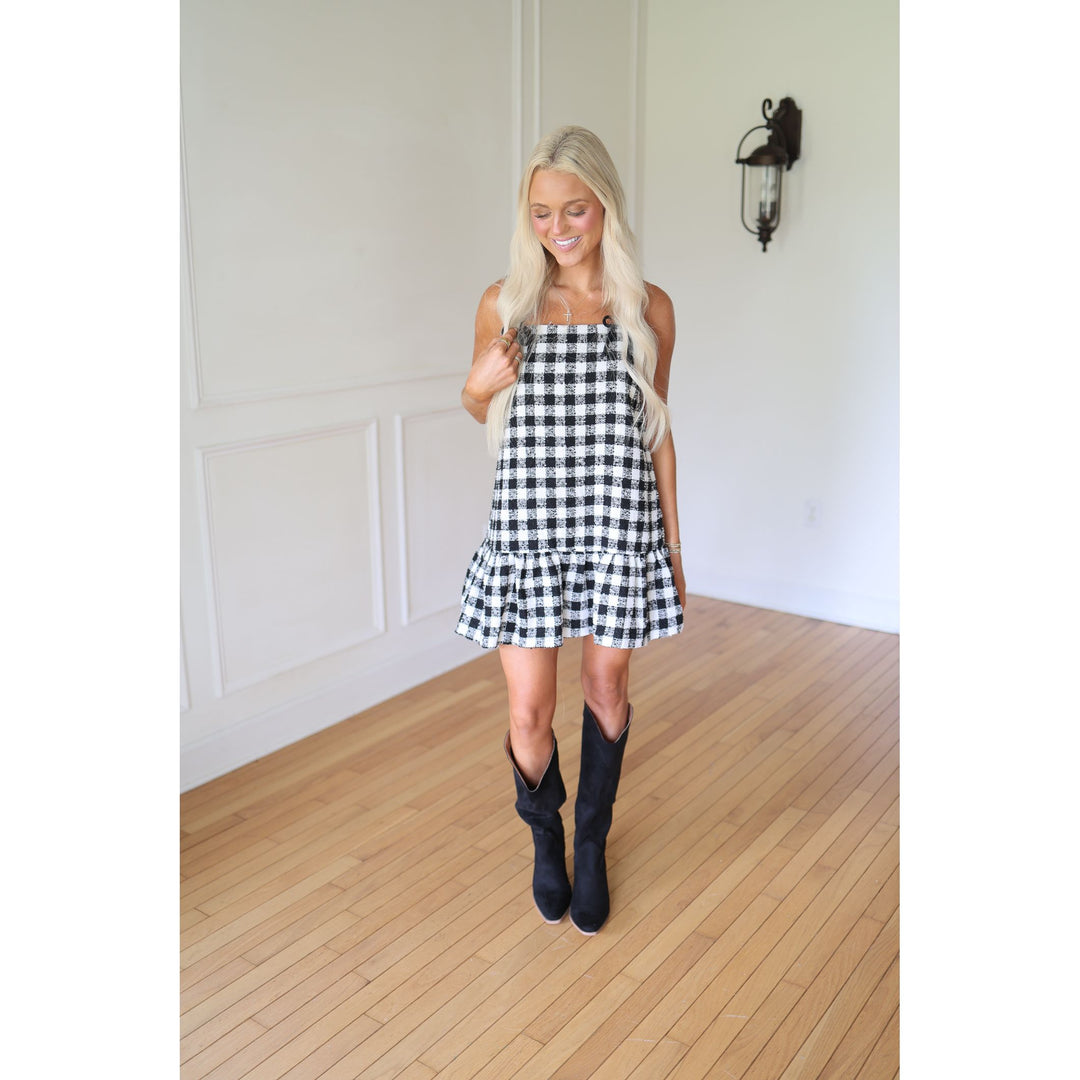 Woman wearing a black and white checkered dress with black boots