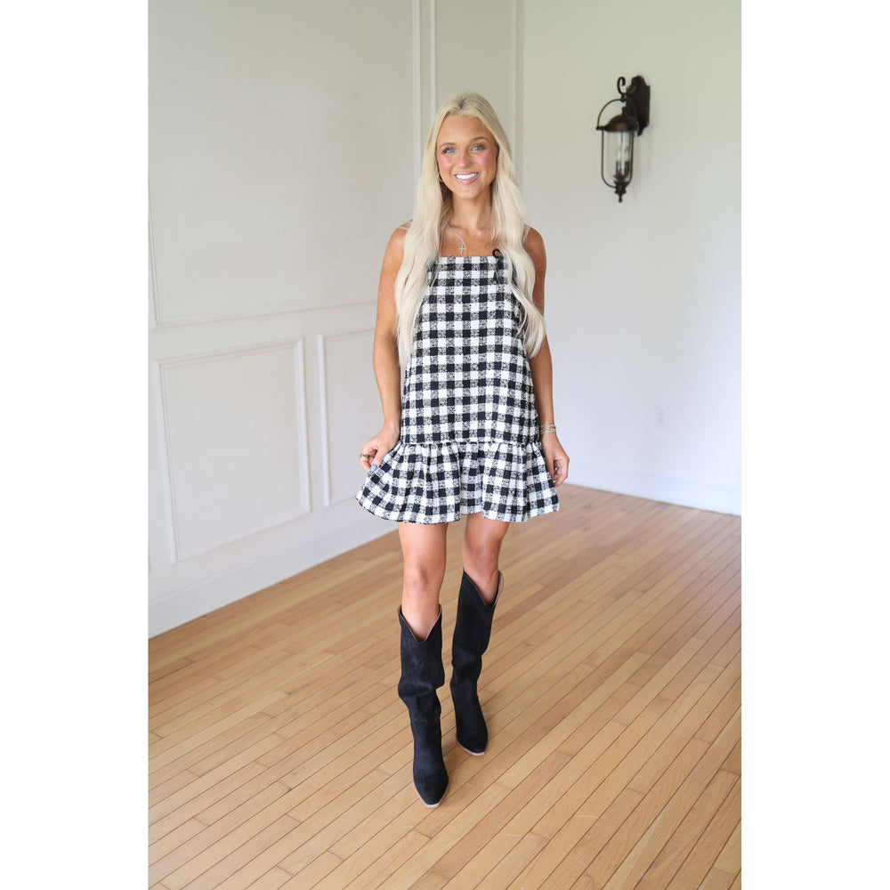Woman wearing a black and white checkered dress with black boots 