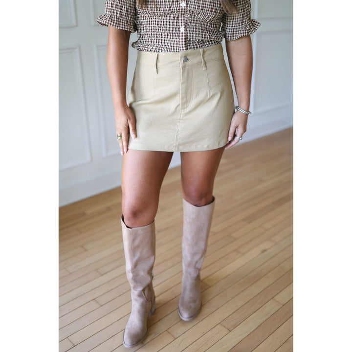 Person wearing a beige skirt and knee-high boots 