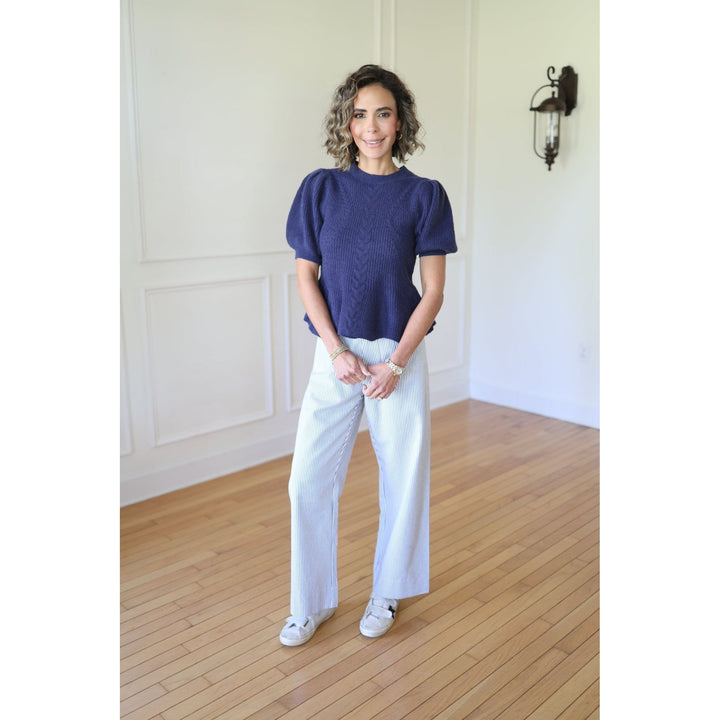 Woman wearing a blue top and white pants 