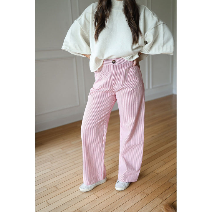 Person wearing a white oversized sweater and red striped pants 