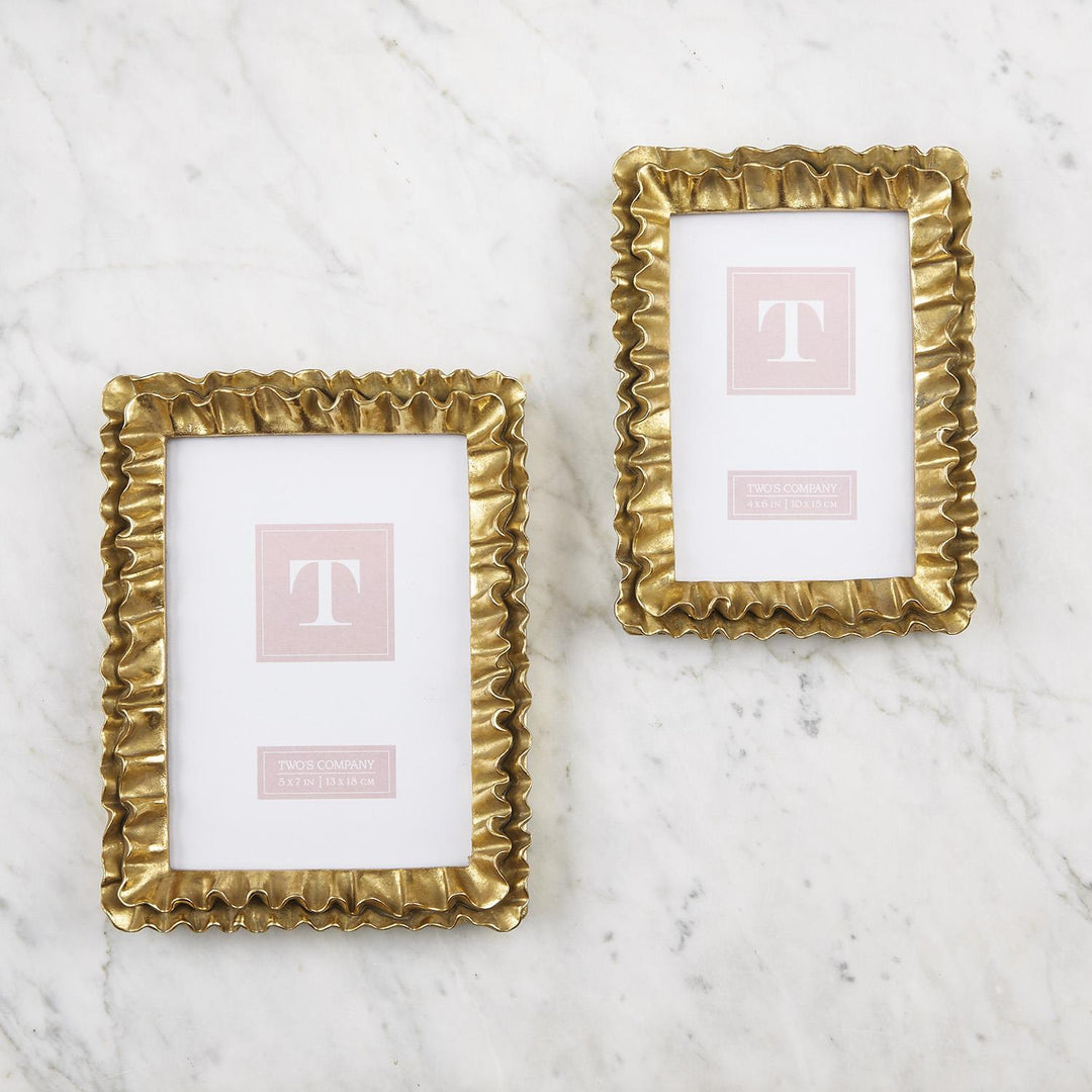 Two gold picture frames with a 'T' on a marble surface