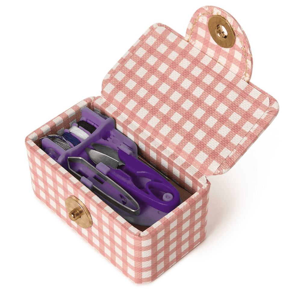 Pink gingham-patterned jewelry box with purple scissors inside on a white background