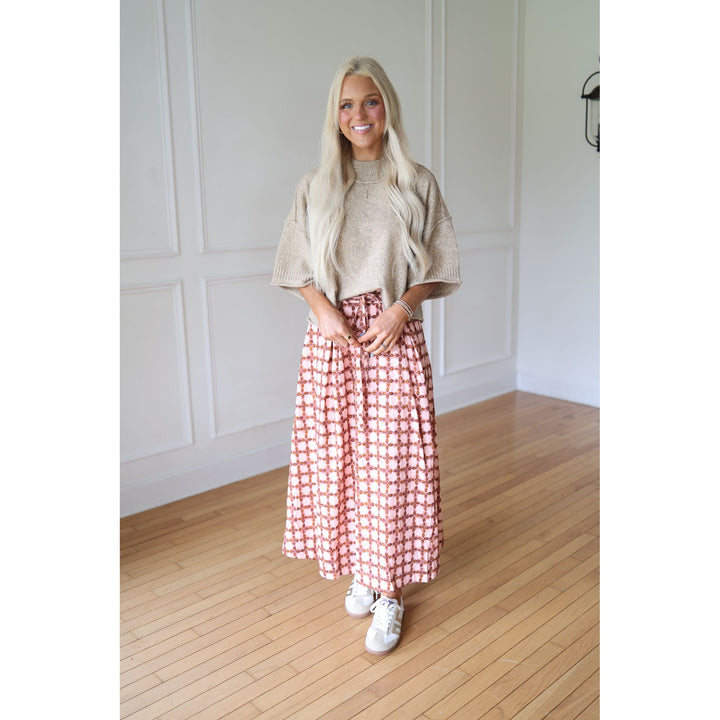 Woman wearing a beige sweater and pink checkered skirt 