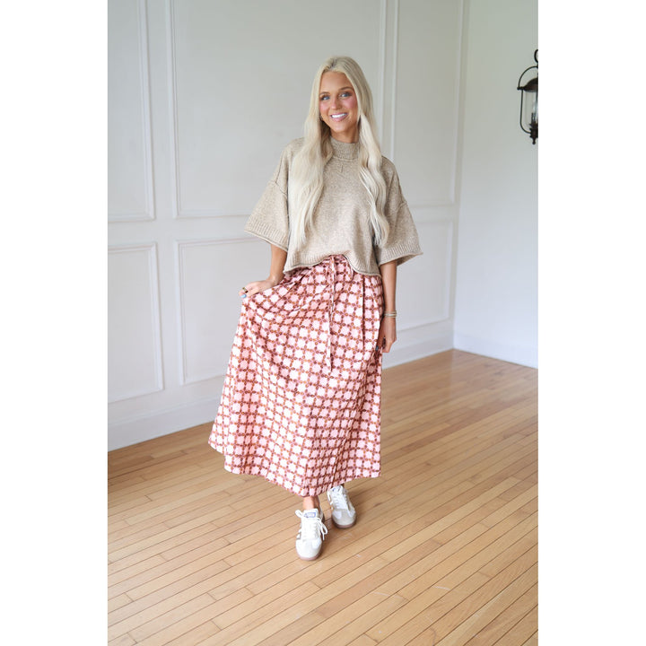 Woman wearing a beige top and checkered skirt 