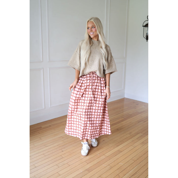 Woman wearing a beige sweater and patterned skirt 