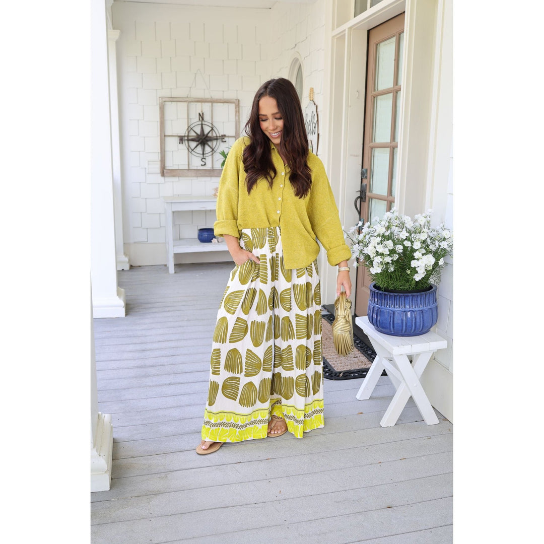 Woman in a yellow and white patterned outfit standing on a porch.